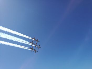 Low angle view of airplane flying against blue sky