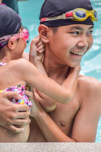 Boy with sister looking away while enjoying in swimming pool