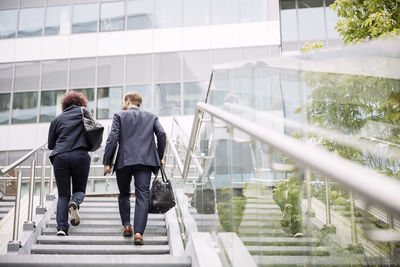 Rear view of people walking on staircase in building