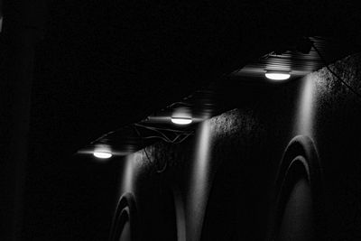 Low angle view of illuminated lights hanging from ceiling in darkroom