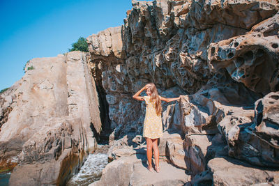 Woman standing on rock against sky