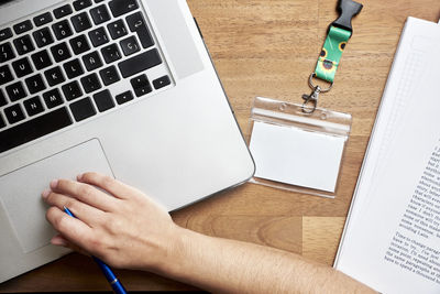 Cropped hands of woman using laptop on table