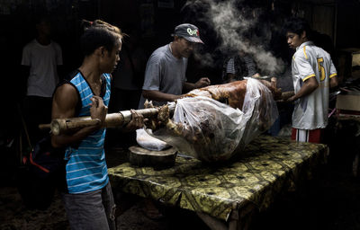 Men cooking pork on table