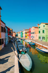 Canal amidst buildings against clear blue sky