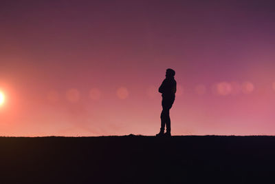 Silhouette woman standing against sky during sunset