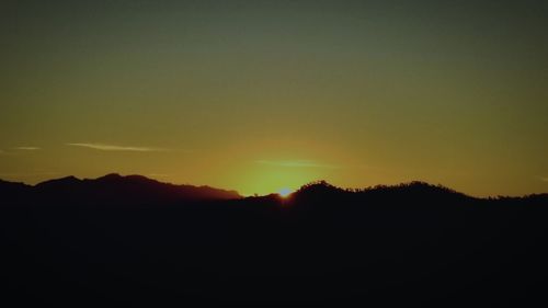 Scenic view of silhouette mountains against clear sky during sunset