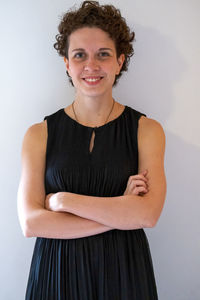 Portrait of smiling young woman standing against wall