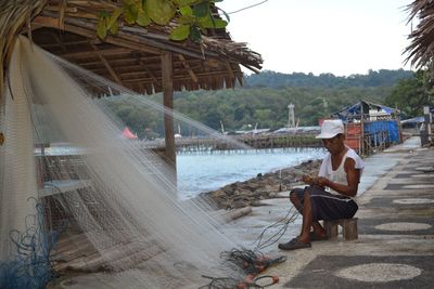 Fisherman weaving net while sitting outdoors