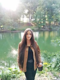 Portrait of smiling young woman standing against trees