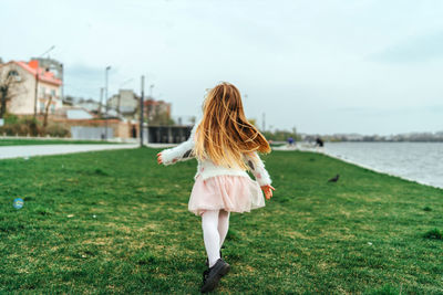 Rear view of woman walking on field against sky