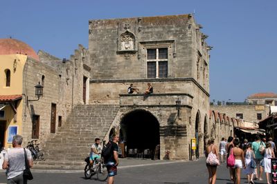 People at historic building against clear sky