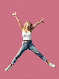 Portrait of young woman jumping against red background