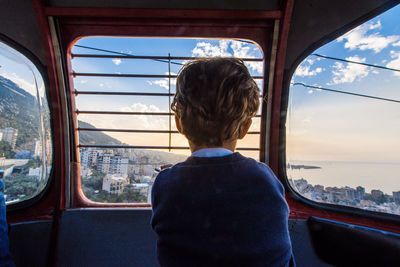 Rear view of boy looking through cable car window