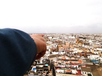 Midsection of man holding townscape against sky in city