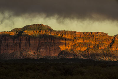 Scenic view of rocky mountains against cloudy sky during sunset