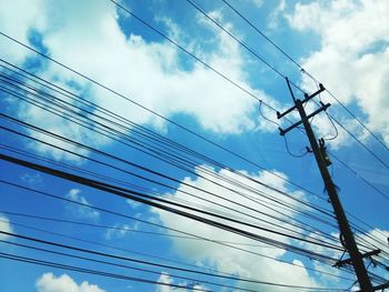 Low angle view of electricity pylon against blue sky