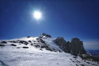 Low angle view of snowcapped mountains against blue sky