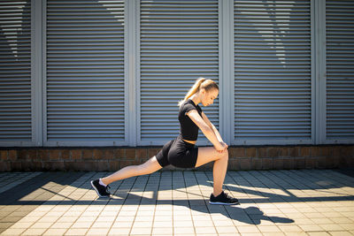 Woman doing warm-up before jogging, stretching leg muscles