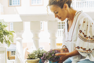 Side view of young woman using mobile phone while sitting at home