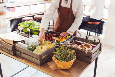 Midsection of male owner arranging vegetables at grocery store