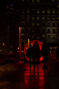 People walking on wet street at night