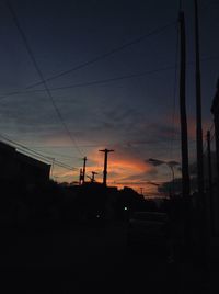 Silhouette electricity pylon against sky at sunset