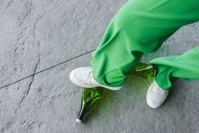 Woman stepping on green plastic bottle