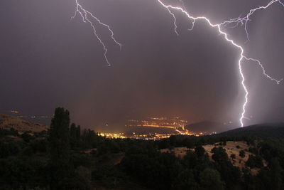 Low angle view of lightning during rainy season at night in city