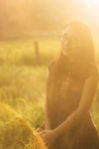 Portrait of young woman on field during sunset
