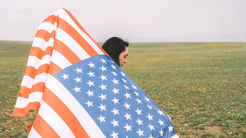 Midsection of woman standing on field against sky