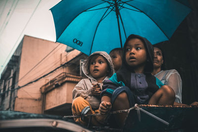 Low angle view of boy sitting on rainy day