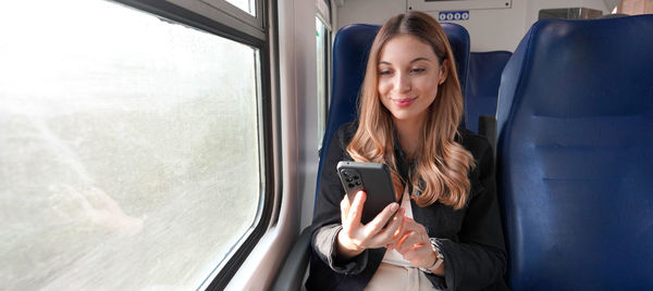 Train female passenger using mobile phone during travel commute.