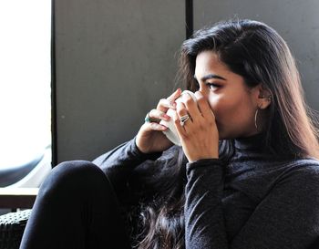 Thoughtful young woman holding coffee cup in cafe