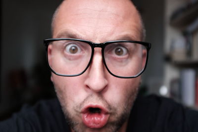 Close-up portrait of angry man wearing eyeglasses at home