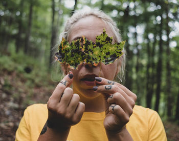 Close-up of woman holding leaf in forest