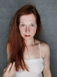 Portrait of young woman standing against wall