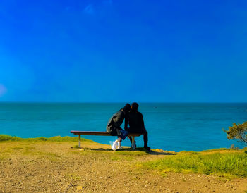 People on beach against clear blue sky