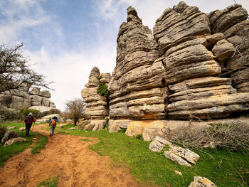 People walking on rock against sky