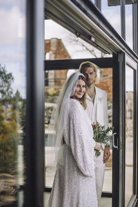 Portrait of newlywed couple standing at entrance hall doorway during wedding