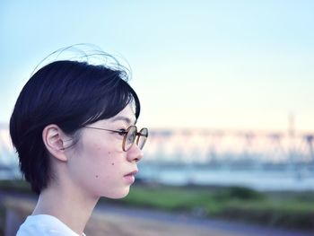 Portrait of young woman looking away against sky