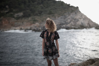 Rear view of woman standing in sea against sky