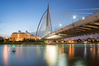 Illuminated bridge over river against sky in city at night