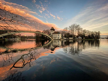 Arch bridge over lake against sky during sunset