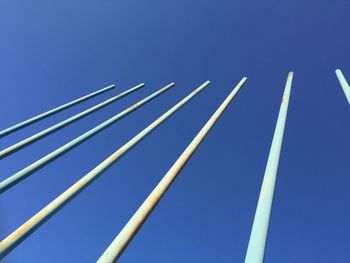 Low angle view of poles against clear blue sky