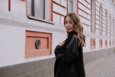 Portrait of woman standing against building