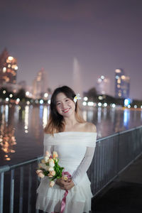 Portrait of young woman standing against illuminated christmas