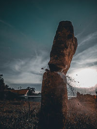 Rocks on field against sky at dusk