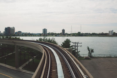 Railroad track passing through city against cloudy sky