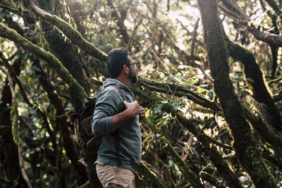 Man looking at tree trunk in forest