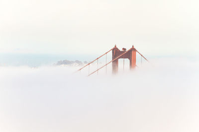 Low angle view of suspension bridge in foggy weather